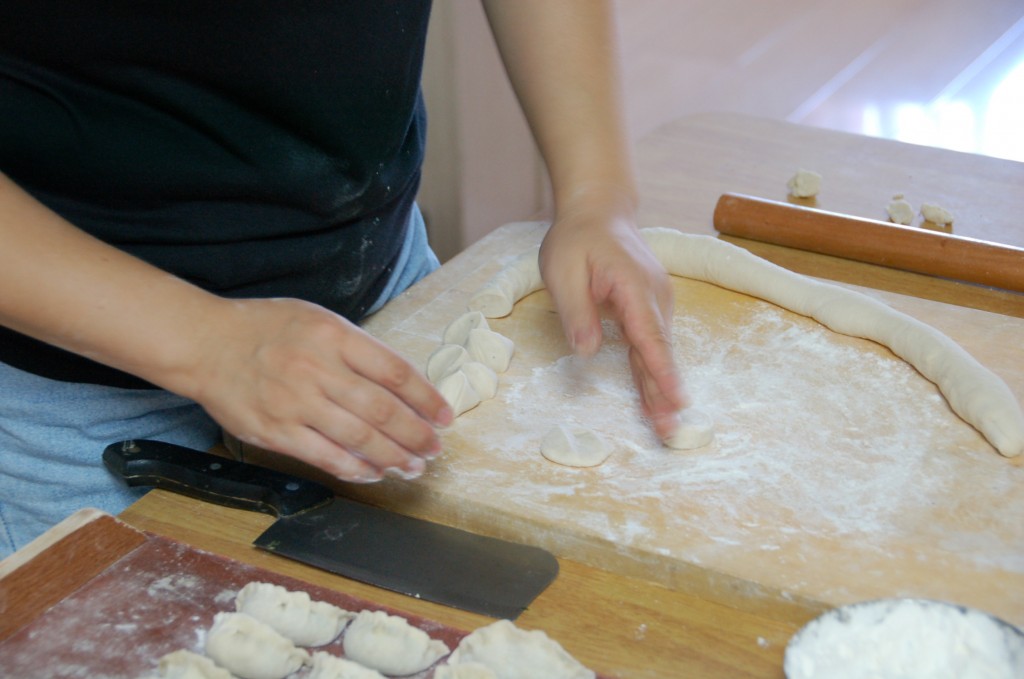 Laurette creating the dumpling skins (and you can also see the stuffed, uncooked dumplings to the left).