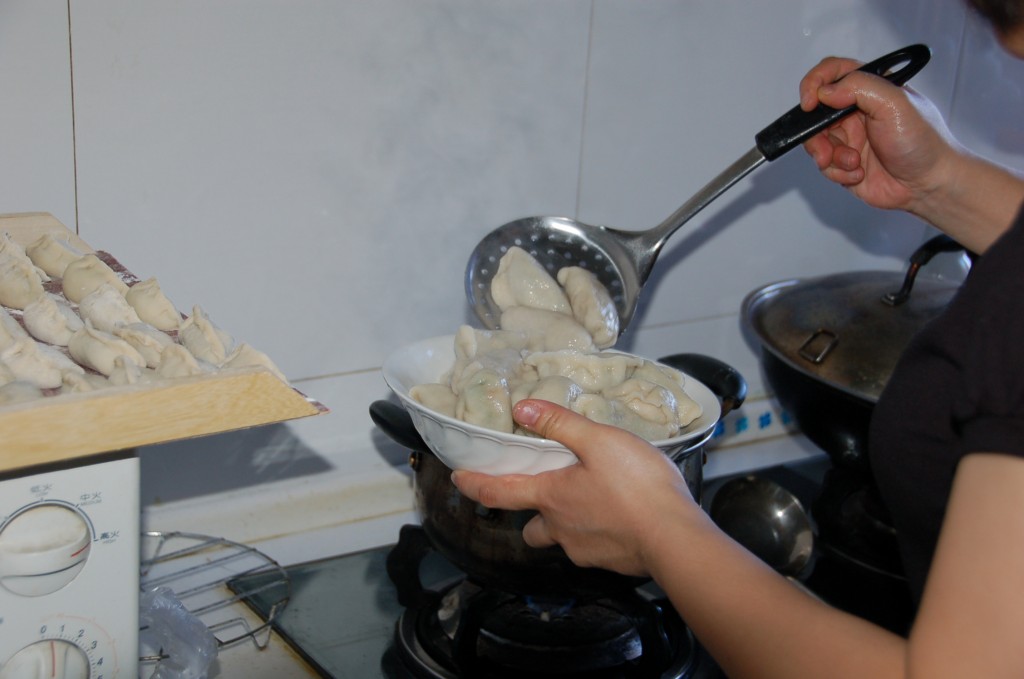 Scooping freshly boiled dumplings (Jiaozi) from boiling water