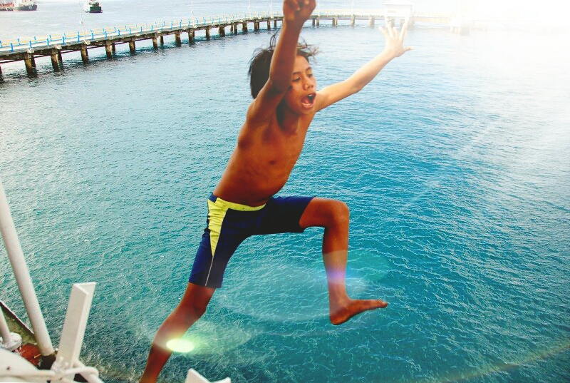 Boy diving off Java to Bali Ferry. Banyuwangi, Indonesia