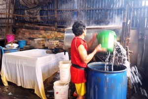 Pouring water into the soy paste prior to sieving. Balikpapan tofu factory, Indonesia